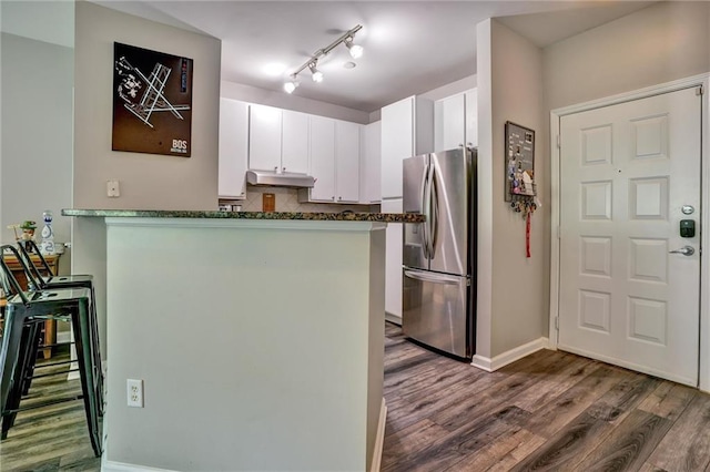 kitchen featuring rail lighting, white cabinets, stainless steel refrigerator, and hardwood / wood-style floors