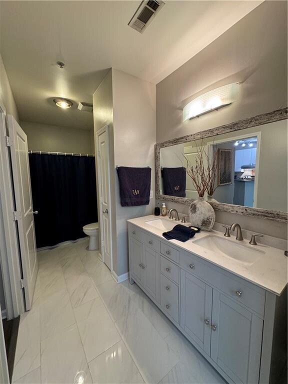 bathroom with dual vanity, toilet, and tile patterned flooring