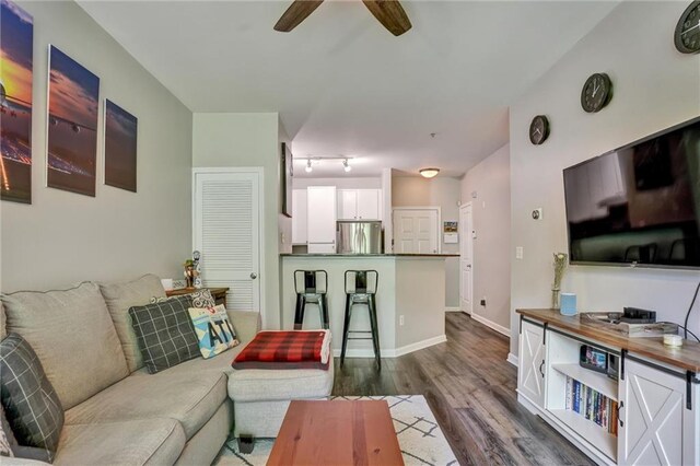 living room featuring ceiling fan and dark hardwood / wood-style flooring