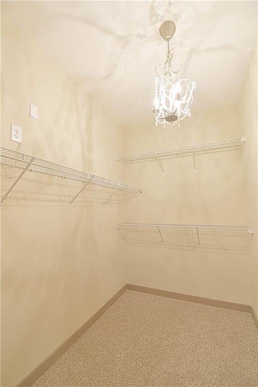 walk in closet featuring a chandelier and carpet flooring