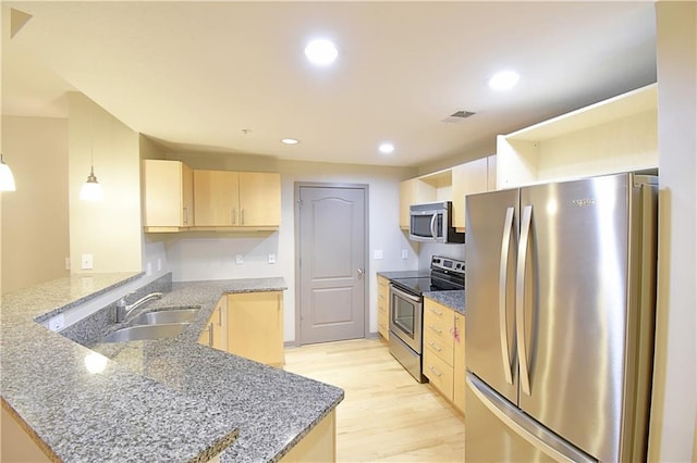 kitchen with light brown cabinets, recessed lighting, a peninsula, stainless steel appliances, and a sink