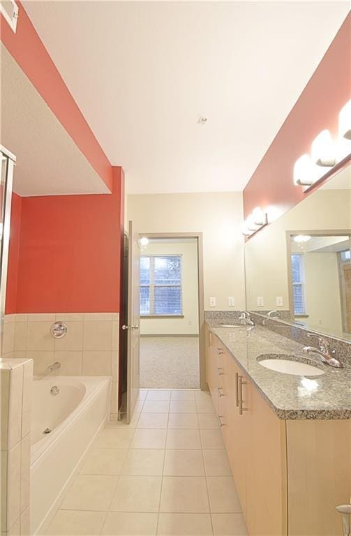 full bath featuring tile patterned floors, double vanity, a garden tub, and a sink