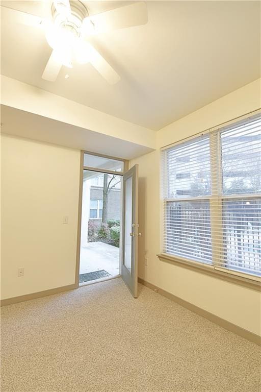 unfurnished room with baseboards, plenty of natural light, light colored carpet, and a ceiling fan