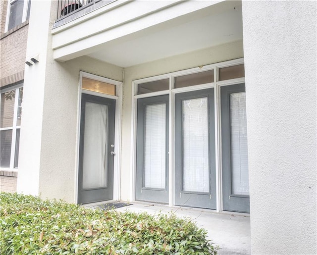 entrance to property with stucco siding and a balcony