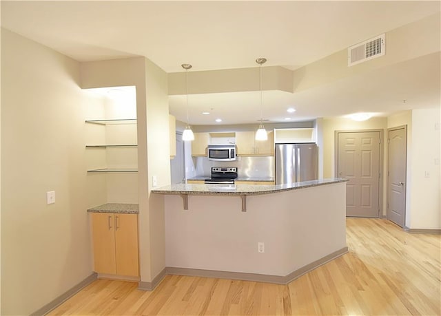 kitchen featuring light wood finished floors, visible vents, light stone counters, a peninsula, and stainless steel appliances