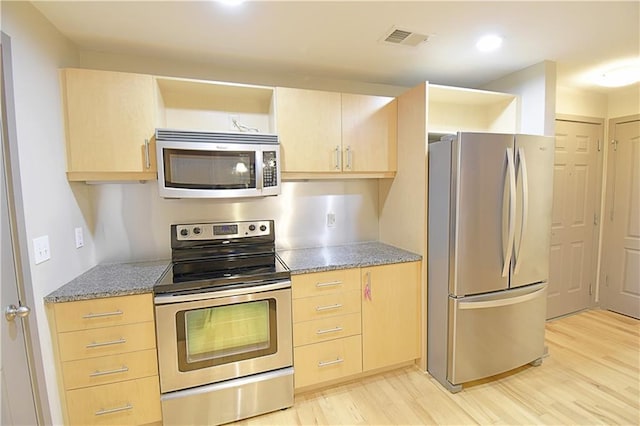 kitchen with visible vents, light brown cabinetry, light wood-type flooring, light stone counters, and stainless steel appliances