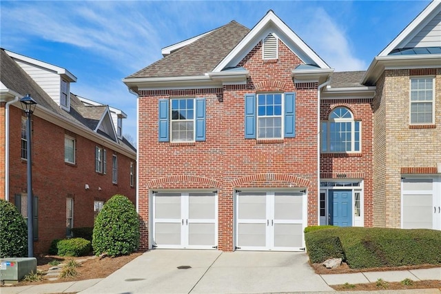 view of front of property featuring brick siding, a garage, driveway, and roof with shingles