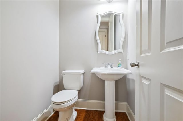 bathroom with a sink, baseboards, toilet, and wood finished floors