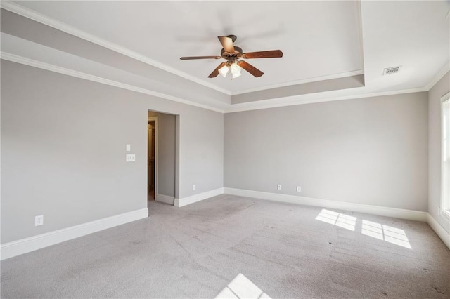 unfurnished room with a ceiling fan, baseboards, carpet floors, ornamental molding, and a raised ceiling