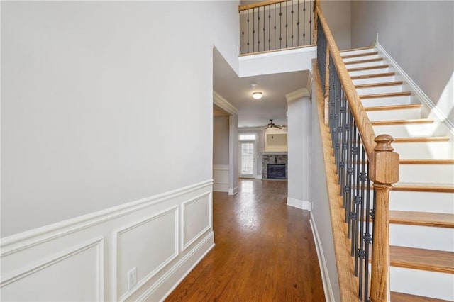 interior space featuring stairway, wood finished floors, wainscoting, crown molding, and a decorative wall