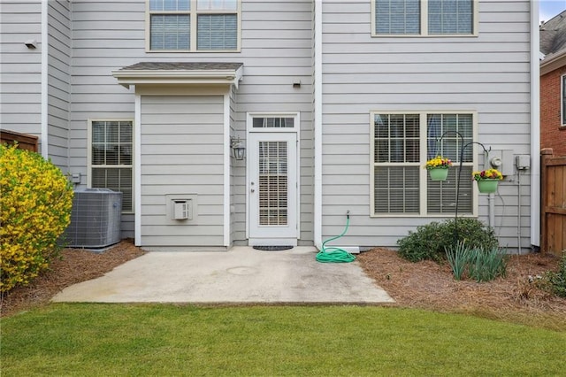 property entrance with a patio area, central air condition unit, and fence