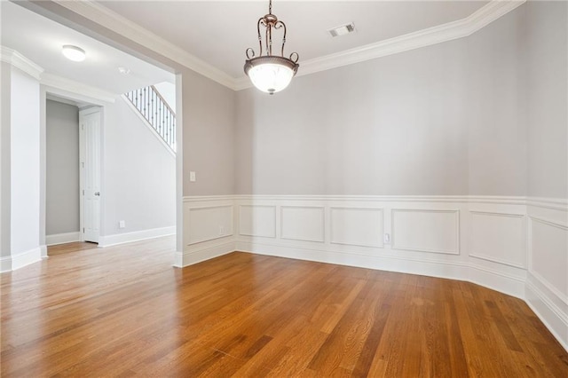 unfurnished room featuring visible vents, wood finished floors, and crown molding