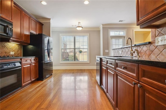 kitchen featuring baseboards, a sink, black appliances, light wood-style floors, and crown molding