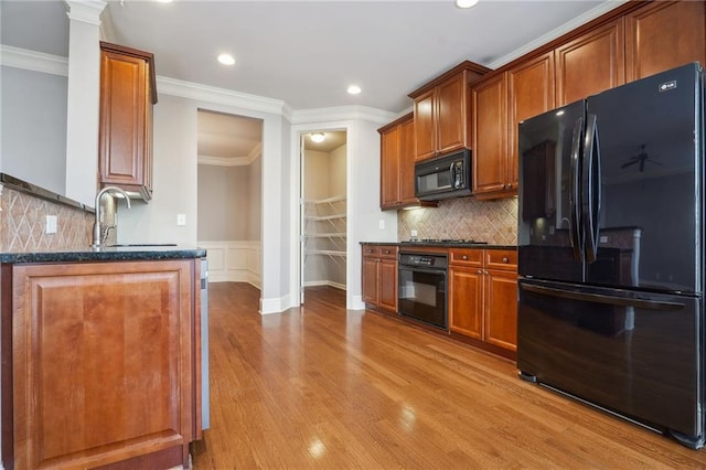 kitchen with black appliances, crown molding, light wood-style floors, and a sink