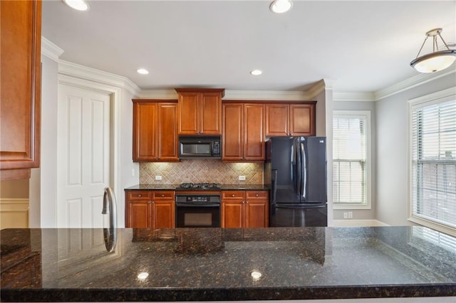 kitchen with dark stone countertops, brown cabinets, black appliances, crown molding, and tasteful backsplash