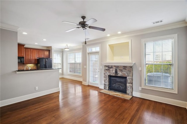 unfurnished living room with a fireplace, dark wood-style flooring, a wealth of natural light, and ornamental molding