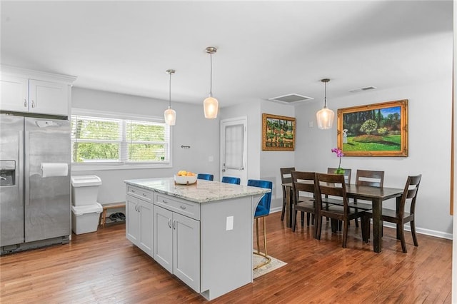 kitchen featuring white cabinets, wood finished floors, visible vents, and stainless steel refrigerator with ice dispenser