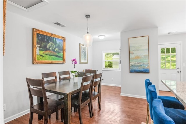 dining space featuring wood finished floors, visible vents, and baseboards