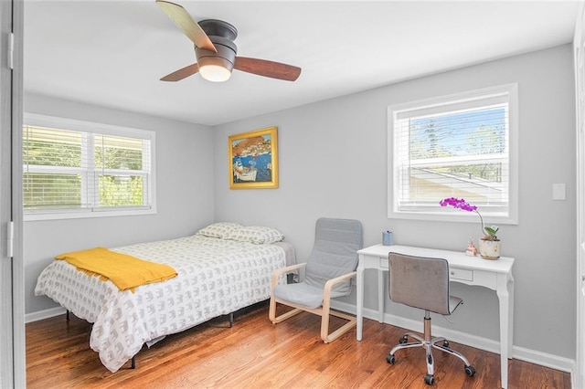 bedroom featuring baseboards, wood finished floors, and multiple windows