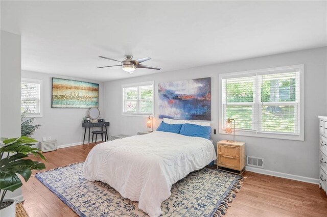 bedroom featuring baseboards, a ceiling fan, visible vents, and light wood-type flooring