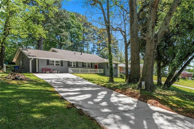 ranch-style house with brick siding, covered porch, a front yard, and concrete driveway