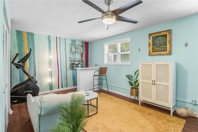living area with wood finished floors, a ceiling fan, and baseboards