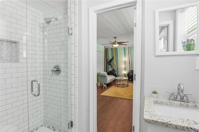 ensuite bathroom featuring a shower stall, wood finished floors, vanity, ensuite bath, and ceiling fan