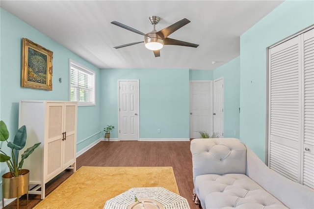 sitting room with baseboards, dark wood-style floors, and ceiling fan