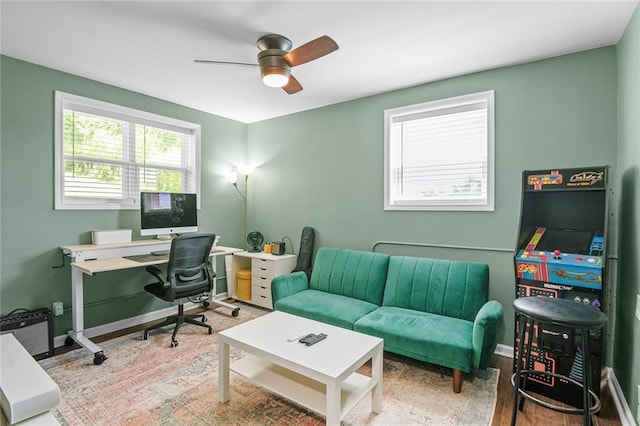 office featuring wood finished floors, a ceiling fan, and baseboards