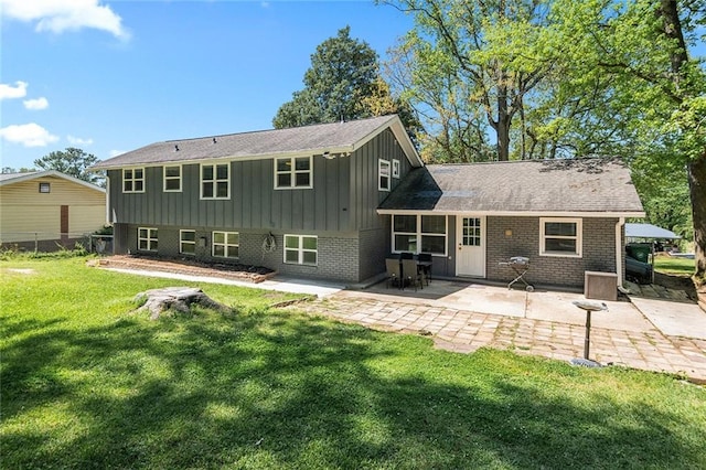 rear view of house with board and batten siding, fence, a yard, a patio, and brick siding