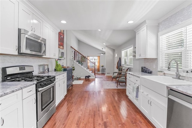 kitchen featuring white cabinets, light wood-style flooring, stainless steel appliances, and a sink