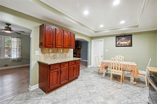 kitchen with ceiling fan, decorative backsplash, light hardwood / wood-style flooring, and crown molding