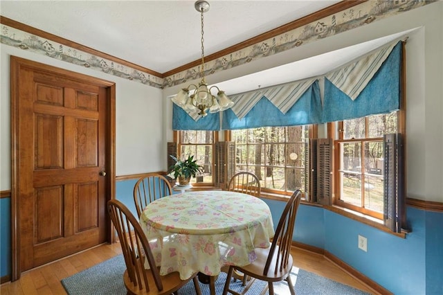 dining area with an inviting chandelier, ornamental molding, and light hardwood / wood-style floors