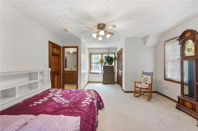 bedroom with ensuite bath, sink, ceiling fan, light carpet, and a textured ceiling