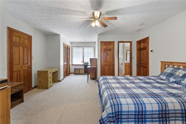 bedroom with ceiling fan, light colored carpet, and a textured ceiling