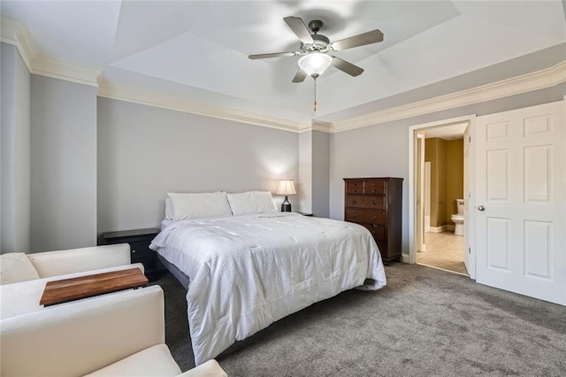 carpeted bedroom featuring a raised ceiling, ceiling fan, ensuite bathroom, and ornamental molding