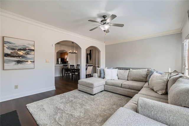 living room with dark hardwood / wood-style floors, ornamental molding, and ceiling fan with notable chandelier