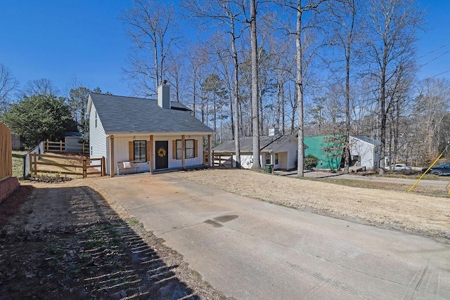 exterior space featuring roof with shingles, a chimney, and fence