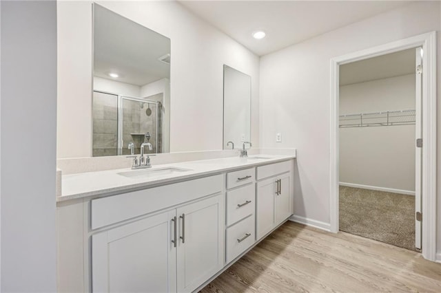 1539 High Falls Ln, Grayson, GA 30017 - bathroom with double vanity, a stall shower, a walk in closet, wood finished floors, and recessed lighting