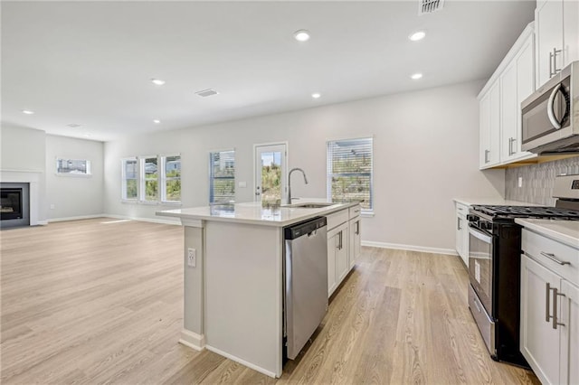 1539 High Falls Ln, Grayson, GA 30017 - kitchen with stainless steel appliances, light wood-style flooring, an island with sink, white cabinetry, and recessed lighting