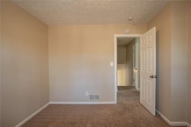 carpeted empty room featuring a textured ceiling