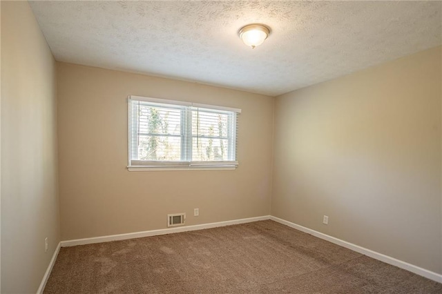 carpeted empty room featuring a textured ceiling