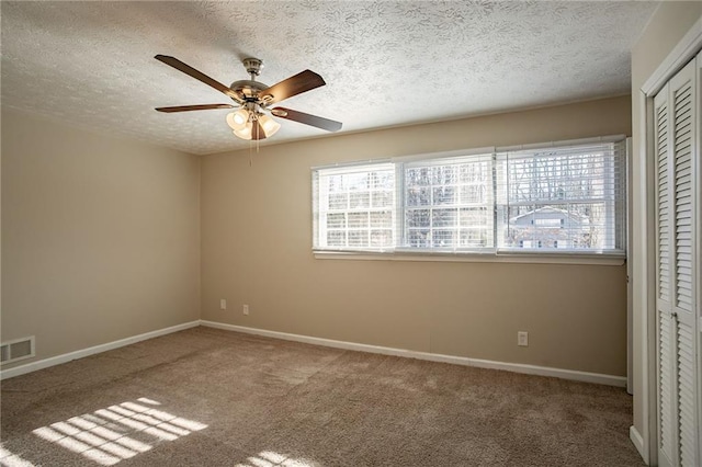 carpeted spare room featuring ceiling fan and a textured ceiling