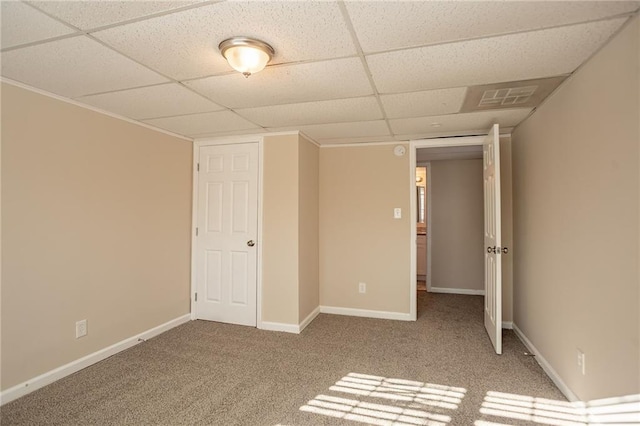 unfurnished bedroom featuring a drop ceiling and light colored carpet