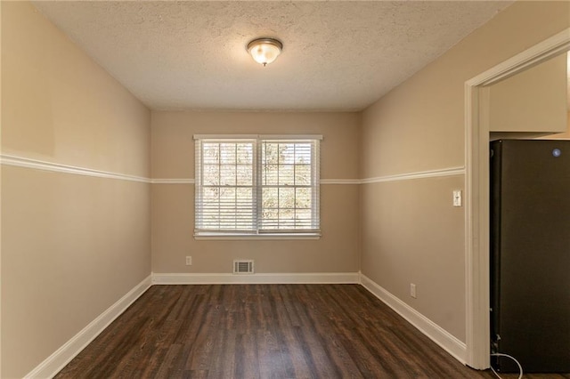 unfurnished room featuring a textured ceiling and dark wood-type flooring