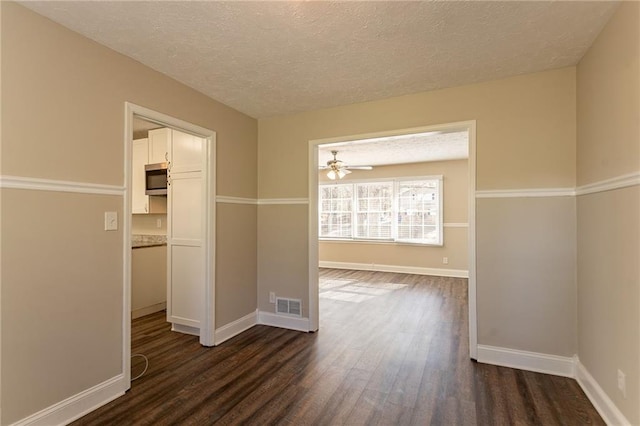 empty room featuring ceiling fan, dark hardwood / wood-style flooring, and a textured ceiling