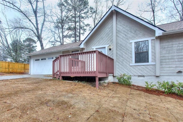 rear view of house with a wooden deck, a garage, and a lawn