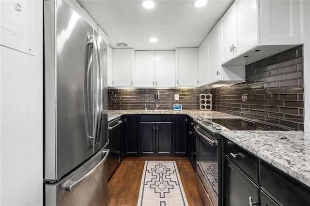 kitchen with freestanding refrigerator, electric stove, a sink, dark wood-style floors, and dark cabinetry