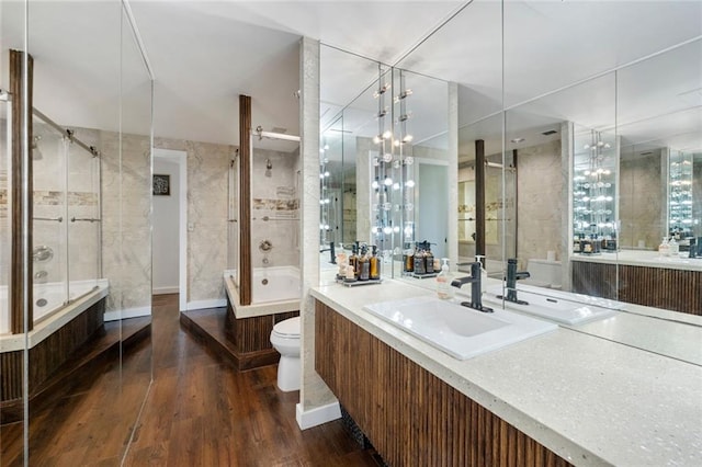 full bathroom with toilet, wood finished floors, a tile shower, a tub to relax in, and vanity