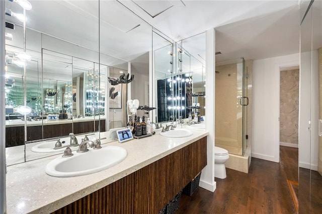 full bath with a stall shower, double vanity, wood finished floors, toilet, and baseboards
